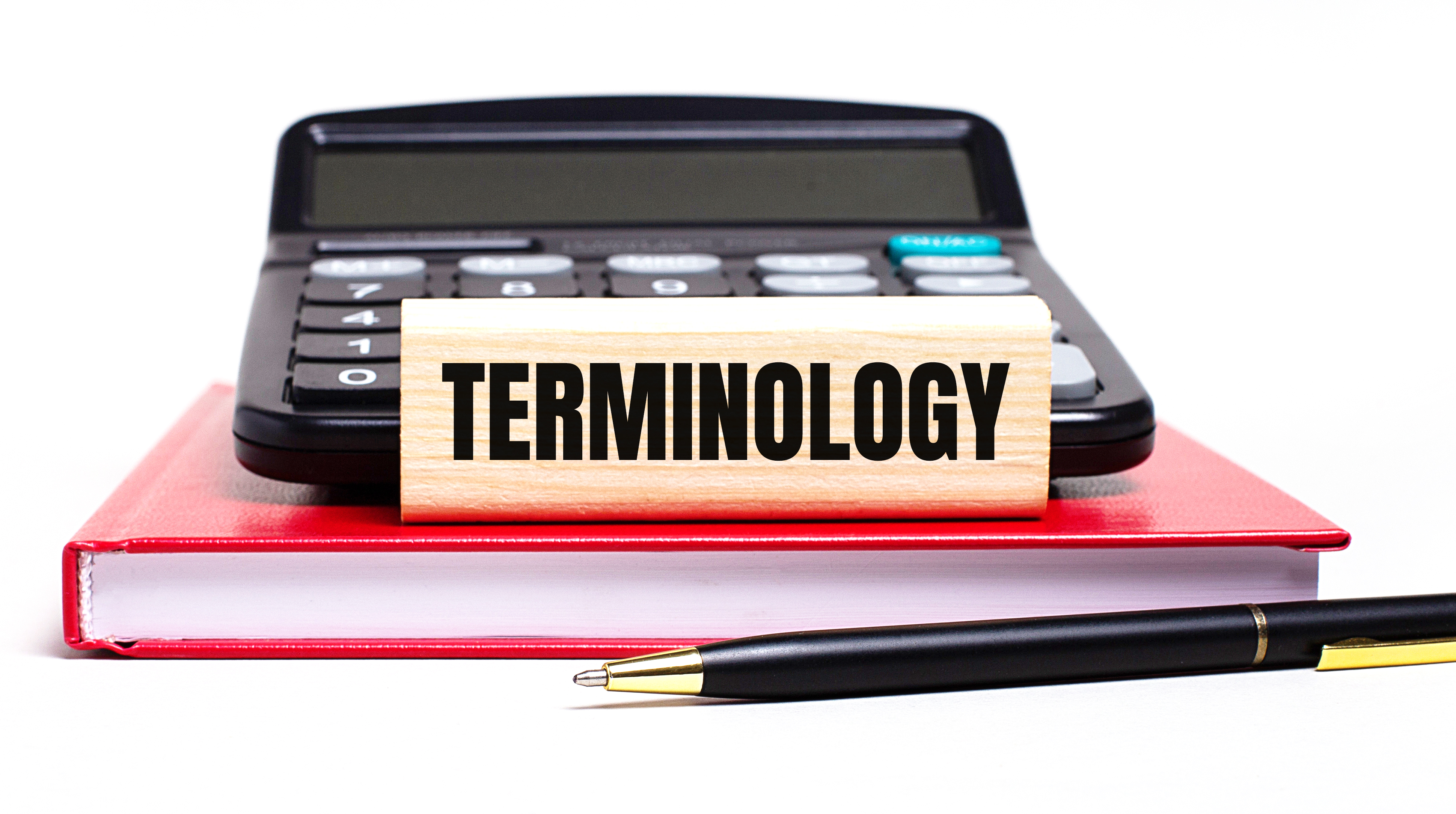 A red book with a pen and calculator. Text saying terminology