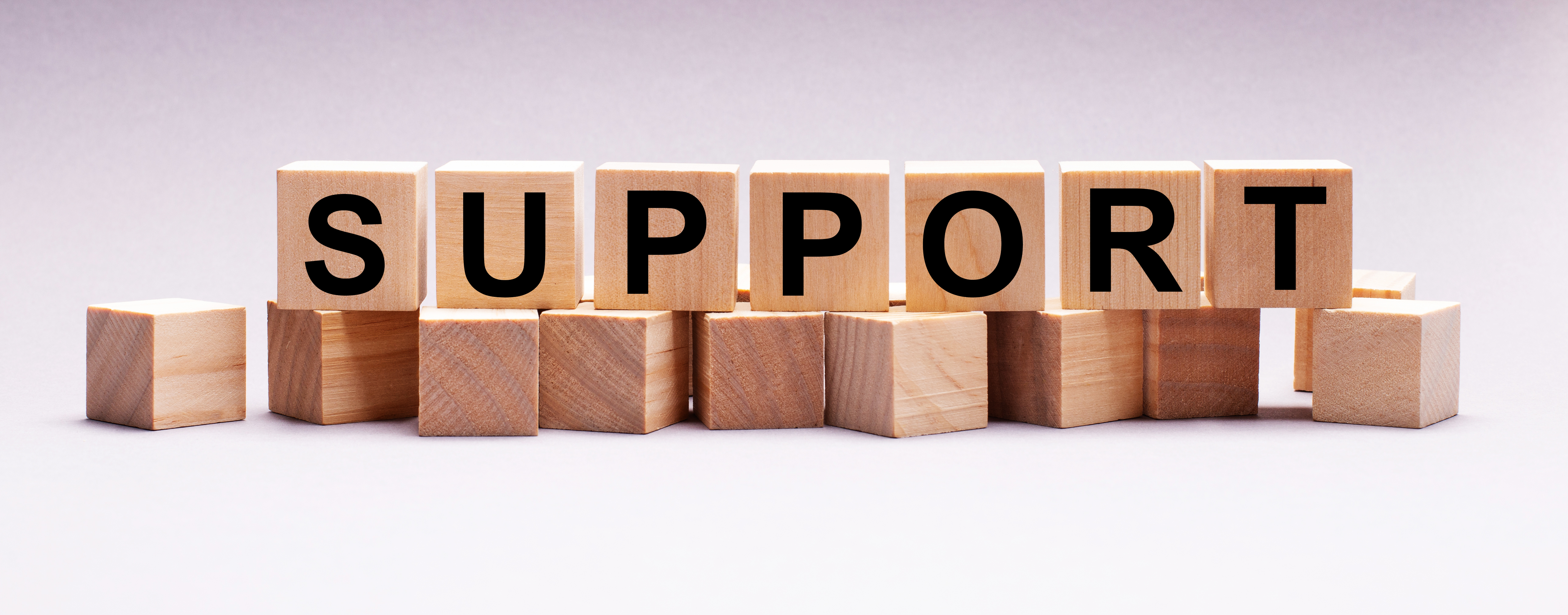 Individual small wooden square blocks each with a letter on that spells out support.